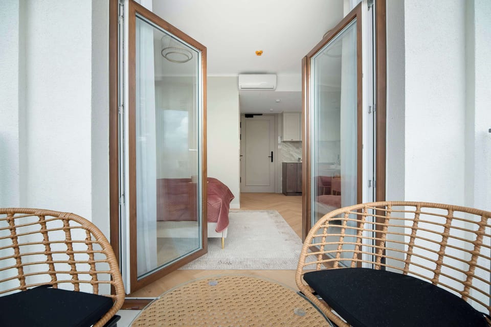 A balcony with two chairs, perfect for relaxing outdoors. Large glass doors connect it to the apartment.
