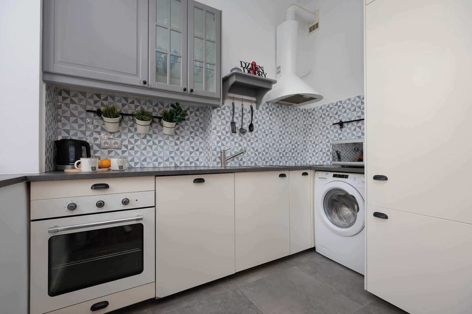 A functional kitchen equipped with an oven, washing machine, and essential cooking facilities. Preparing homemade meals is simple and convenient.