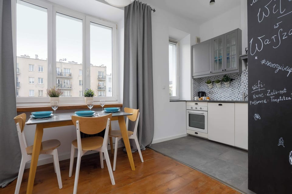 A dining table placed next to large windows creates a pleasant space for meals. The fully equipped kitchen is just beside it for added convenience.