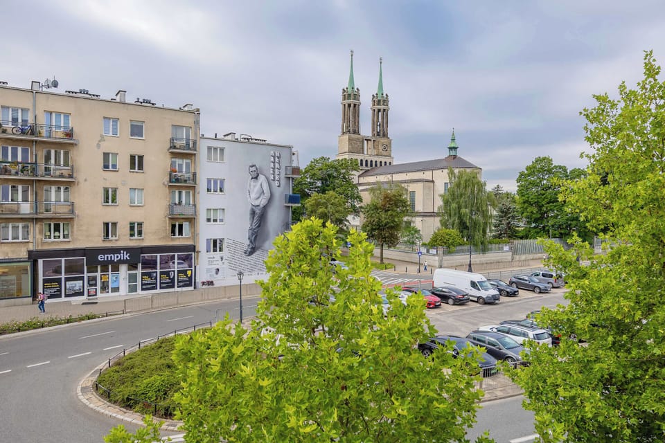 A view of the surrounding neighborhood with residential buildings, greenery, and a church in the distance. The area offers a pleasant urban atmosphere.