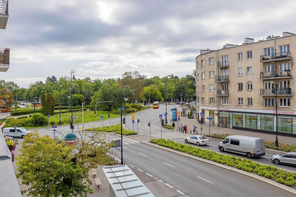 A view overlooking the nearby streets, green spaces, and residential buildings. The surroundings combine city convenience with open views.
