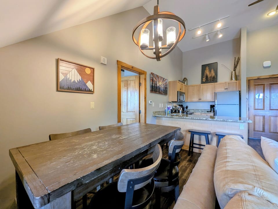 Gather around a handsome rustic dining table with mountain-inspired art and cozy modern fixtures setting the scene for memorable meals together.