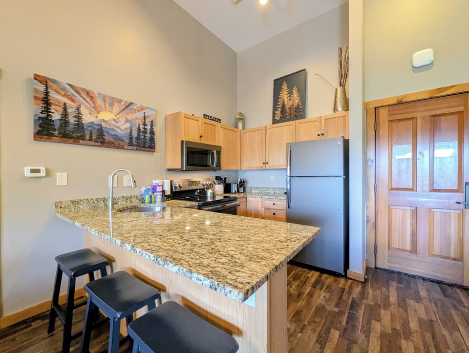 Step into your fully equipped kitchen with granite countertops, stainless steel appliances, and warm wood cabinetry. The spacious island offers the perfect spot for morning coffee or meal prep during your mountain getaway.