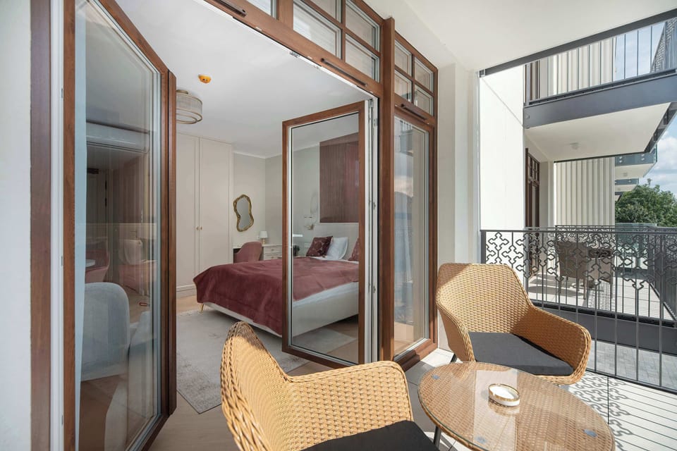 A private balcony offers comfortable chairs and a small table. Large glass doors provide easy access from the apartment.
