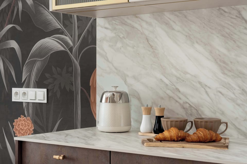 A close-up of the kitchenette highlights the marble-style backsplash and countertop. Decorative details add a modern touch.