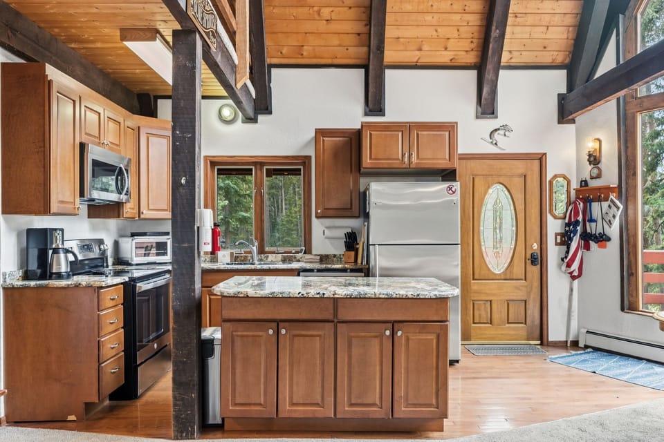 Step into this open-concept retreat where rustic timber beams meet modern convenience. Your fully-equipped kitchen features granite countertops, stainless appliances, and a center island—perfect for preparing mountain meals.