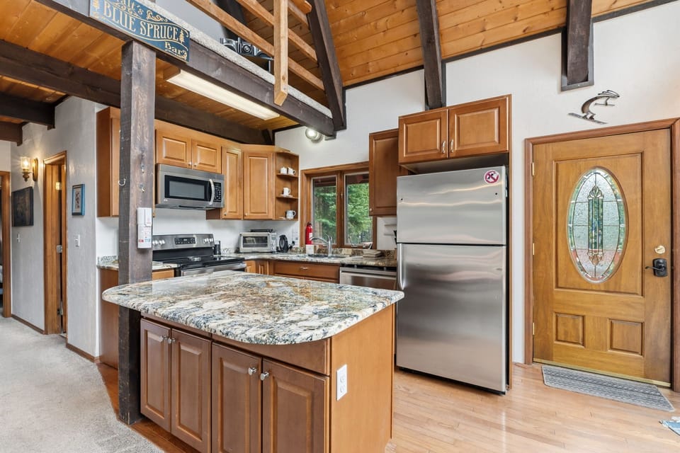 Your spacious kitchen welcomes you with soaring wood-beamed ceilings, granite countertops, and modern stainless appliances. Warm wood tones and an open layout create a cozy, mountain-lodge feel perfect for cooking and gathering.