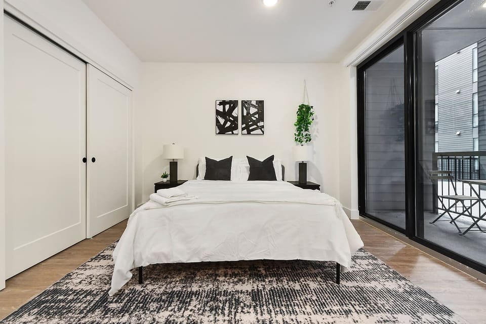 Bright and inviting bedroom with a cozy queen bed and large windows.