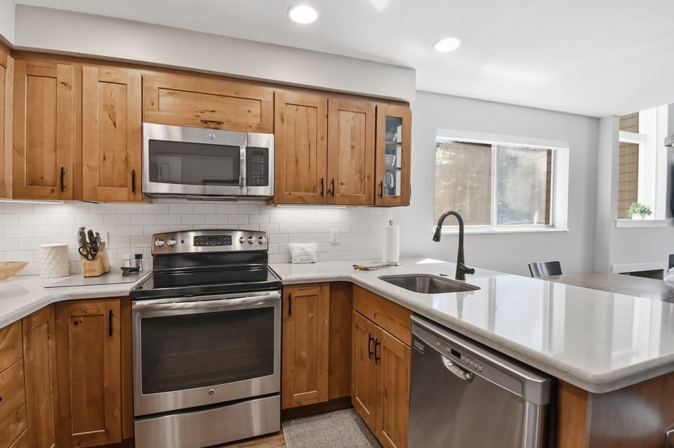Bright, fully equipped kitchen with warm wood cabinetry, modern appliances, and gleaming countertops—perfect for preparing your favorite meals during your stay.