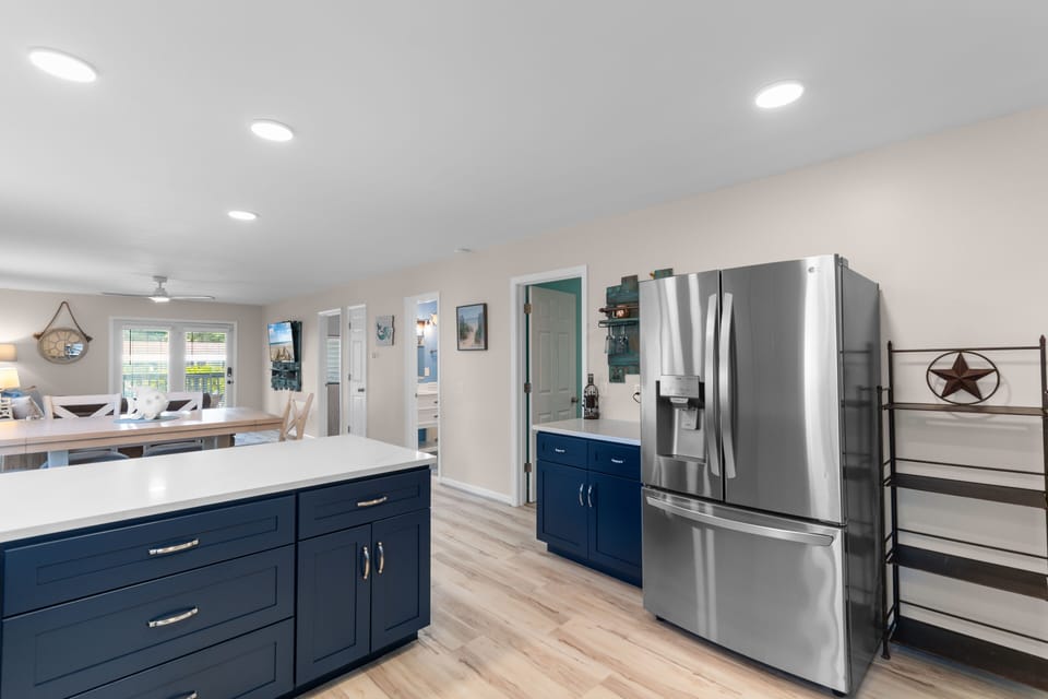 Open-concept kitchen with navy island, stainless refrigerator, and recessed lighting at Ocean Bliss Unit 102, Surfside Beach