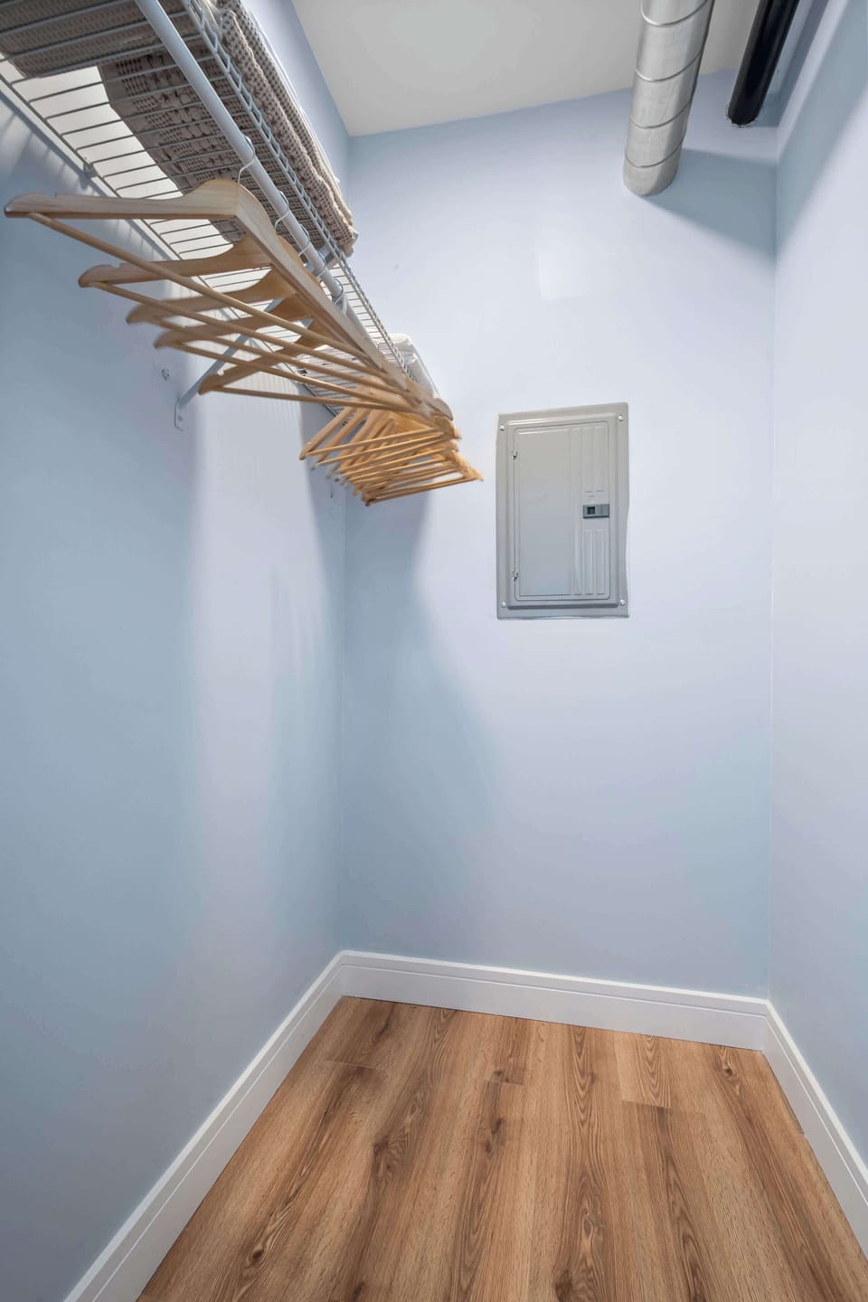 Dedicated walk-in closet with wire shelving, ample wooden hangers, and hardwood floors. Clean, well-lit space with plenty of room to unpack and organize for any length of stay.