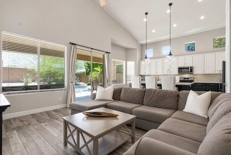 This living room's vaulted ceilings and natural light fill an airy living space, where an oversized sectional and smart TV make for easy movie nights, just steps from sliding doors out to the pool.