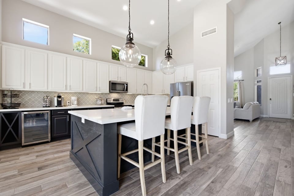The kitchen's two-toned cabinetry and quartz counters wrap around a spacious island with seating for four, all finished with stainless steel appliances and a designer arabesque tile backsplash.