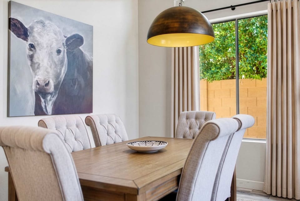 A statement dome pendant sets the tone over the dining area's tufted table for six, framed by soaring ceilings and set just steps from a second cozy lounging area.