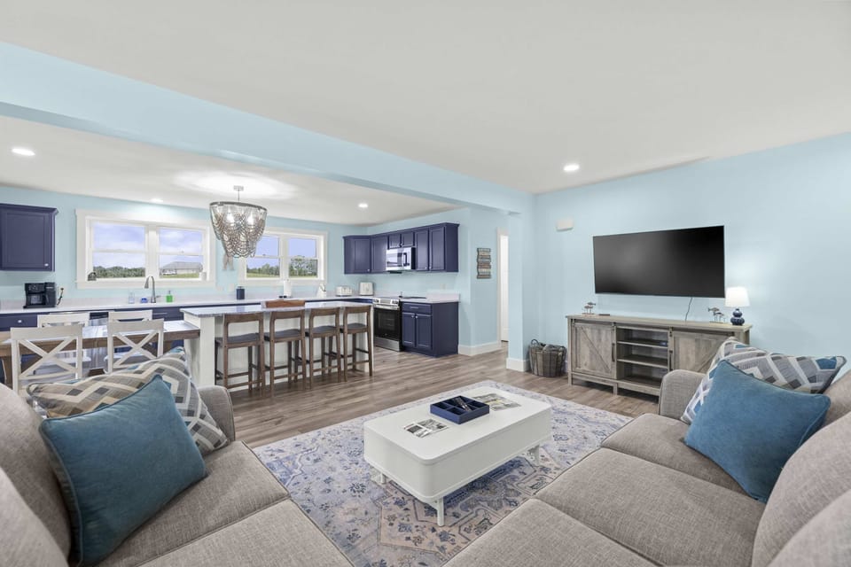 Great Room - From the plush sectional the space opens wide, with island seating for five, a farmhouse dining table, and a wall mounted TV.