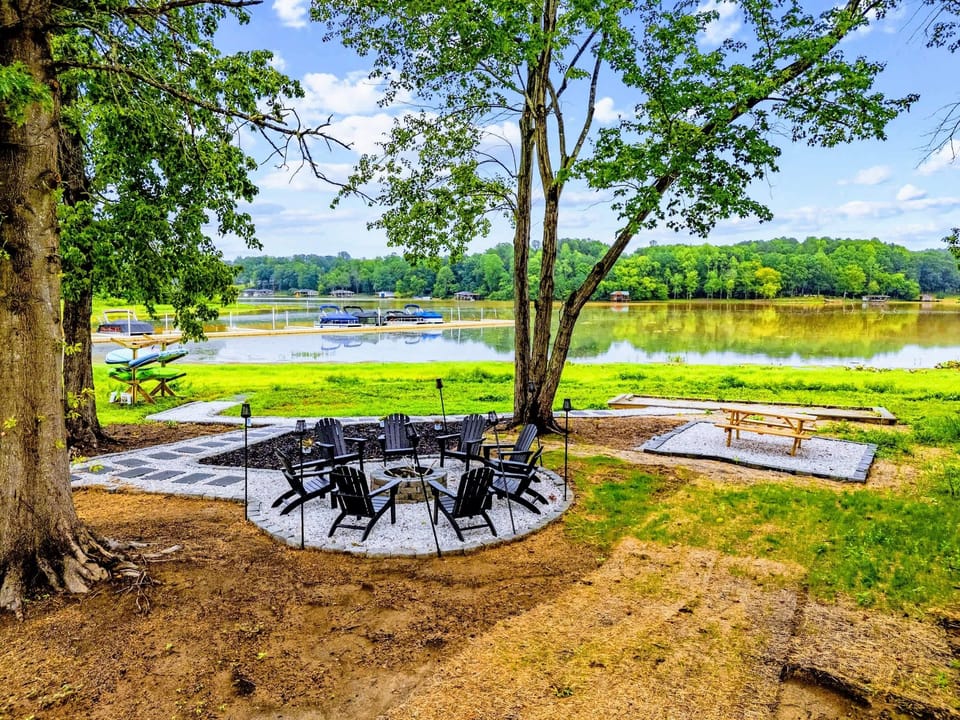Backyard & Beach - The whole waterfront hangout in one frame, fire pit under the trees, picnic table nearby, and boats resting at the slips.