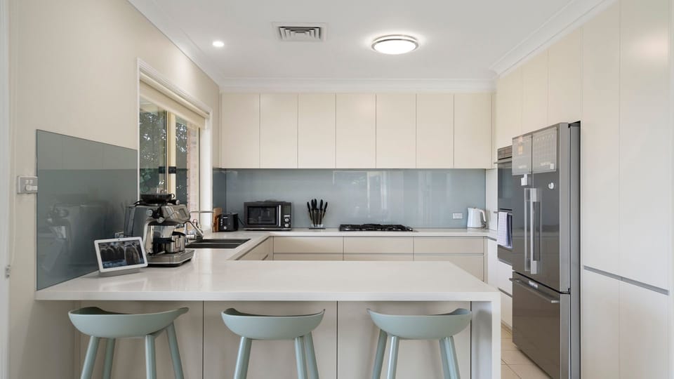 The spacious kitchen features a large island bench, modern appliances, and plenty of room for group meals.