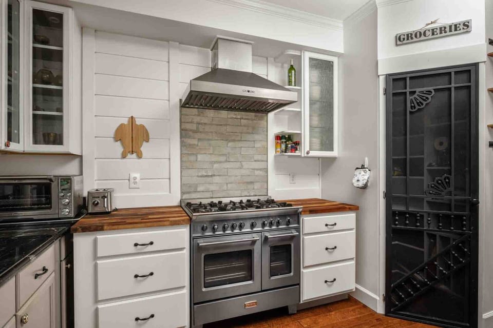A professional-grade gas stove and hood framed by clean white cabinetry.