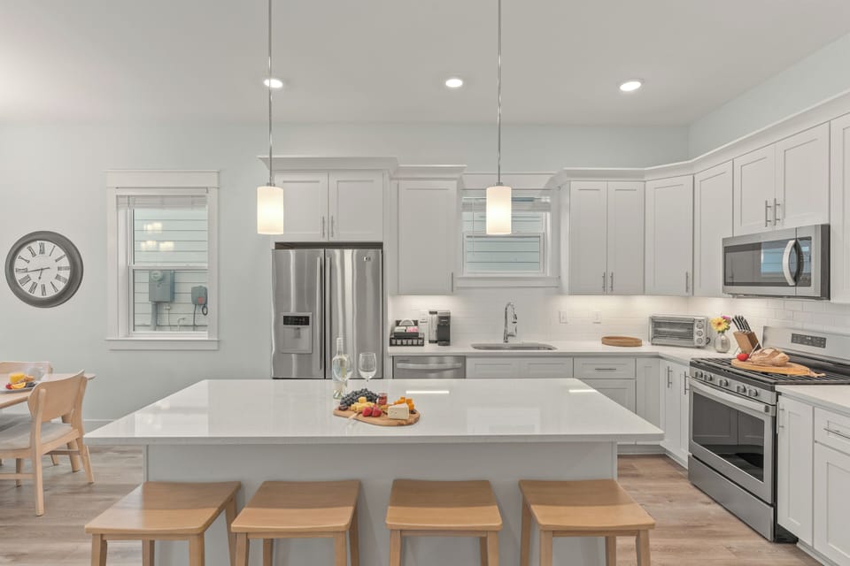 A crisp, modern kitchen features a large island with seating, stainless steel appliances, and plenty of space for group meals.