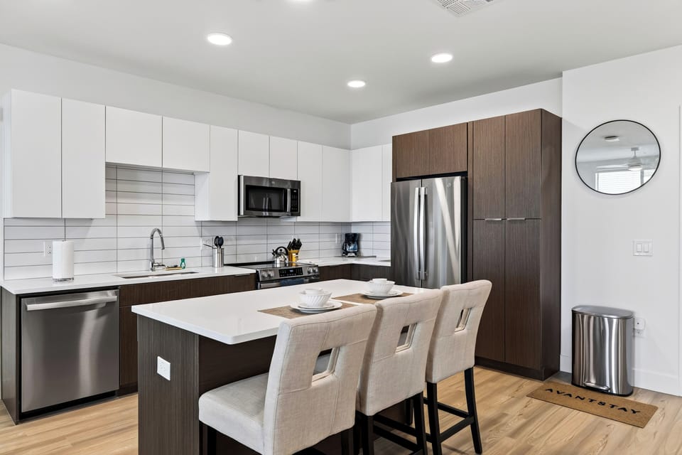 Modern kitchen with island seating and stainless steel appliances.