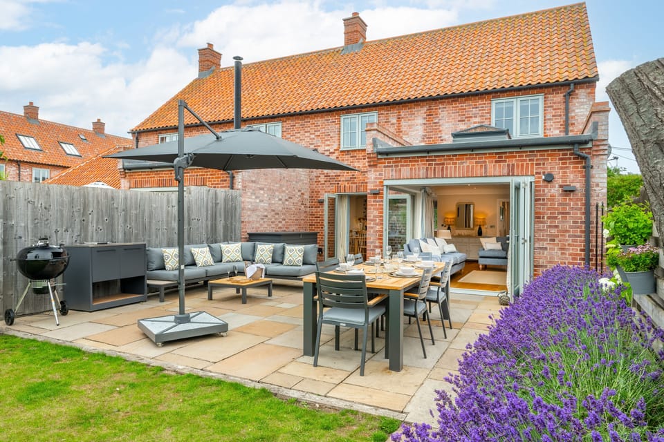 Pretty, enclosed rear garden offers a lawned area, borders, patio, seating and charcoal Webber kettle barbecue