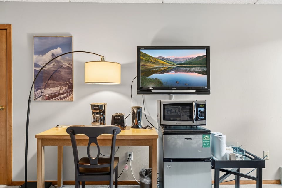 Your cozy workspace features a TV, microwave, mini-fridge, toaster, and coffee maker—please note: this unit does not have a full kitchen.