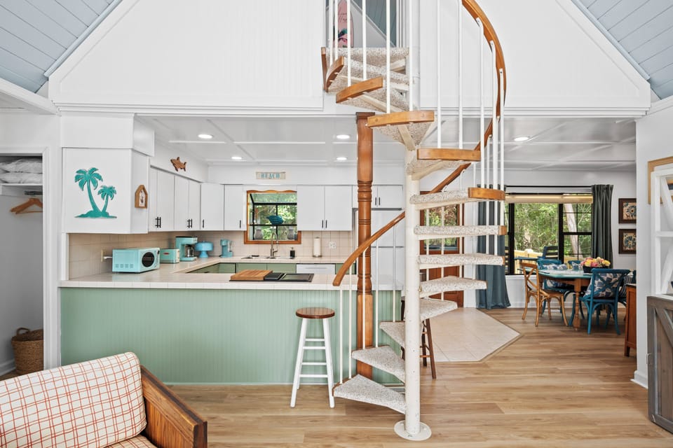 Unwind in your bright, airy retreat where coastal charm meets modern comfort. Cozy up by the spiral staircase or gather in the inviting living and dining spaces, all bathed in natural light.
