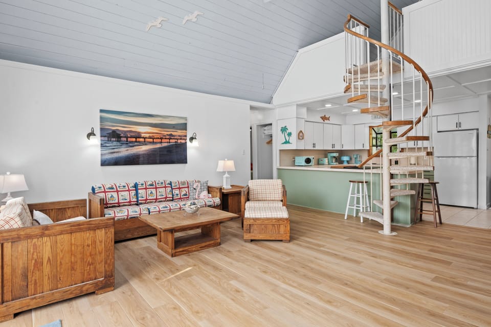 Step into your bright coastal retreat where a charming spiral staircase invites you upward. Relax on the cozy sofa, whip up meals at the breakfast bar, and soak in the breezy beach-house charm all around you.