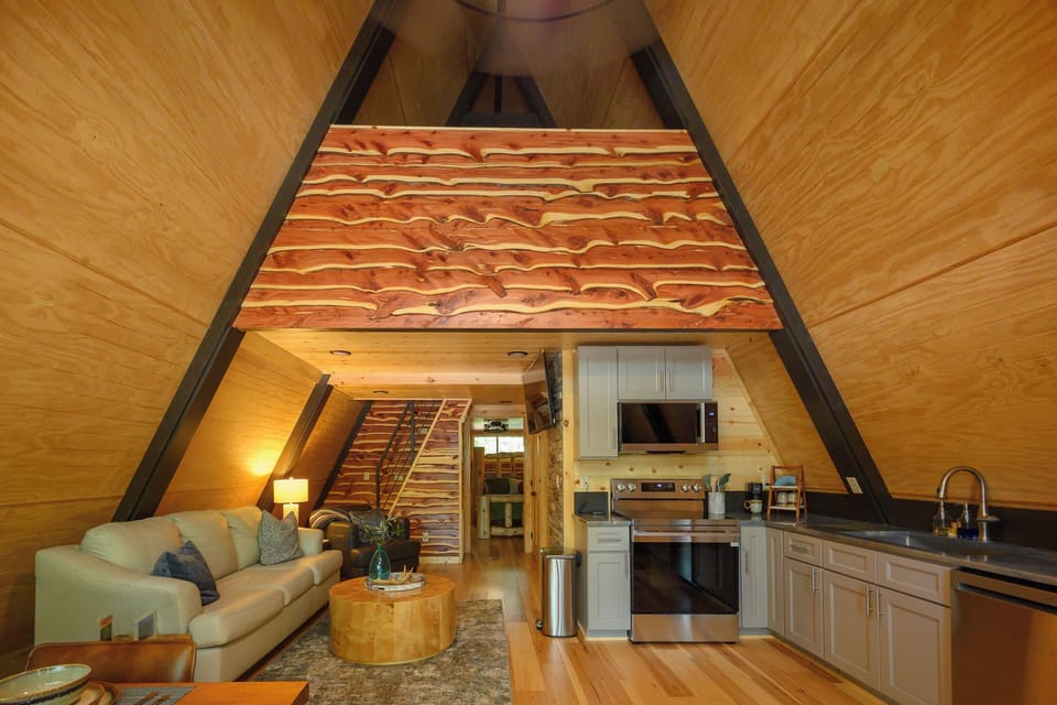 Step into your cozy A-frame retreat, where warm wood tones wrap around you and a unique loft beckons above. Your kitchen stands ready for home-cooked meals, while your living space invites you to unwind by soft lamplight.