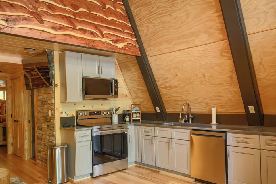 Your A-frame retreat features a full kitchen with modern appliances and warm wood accents, blending rustic charm with all the comforts you need for your stay.