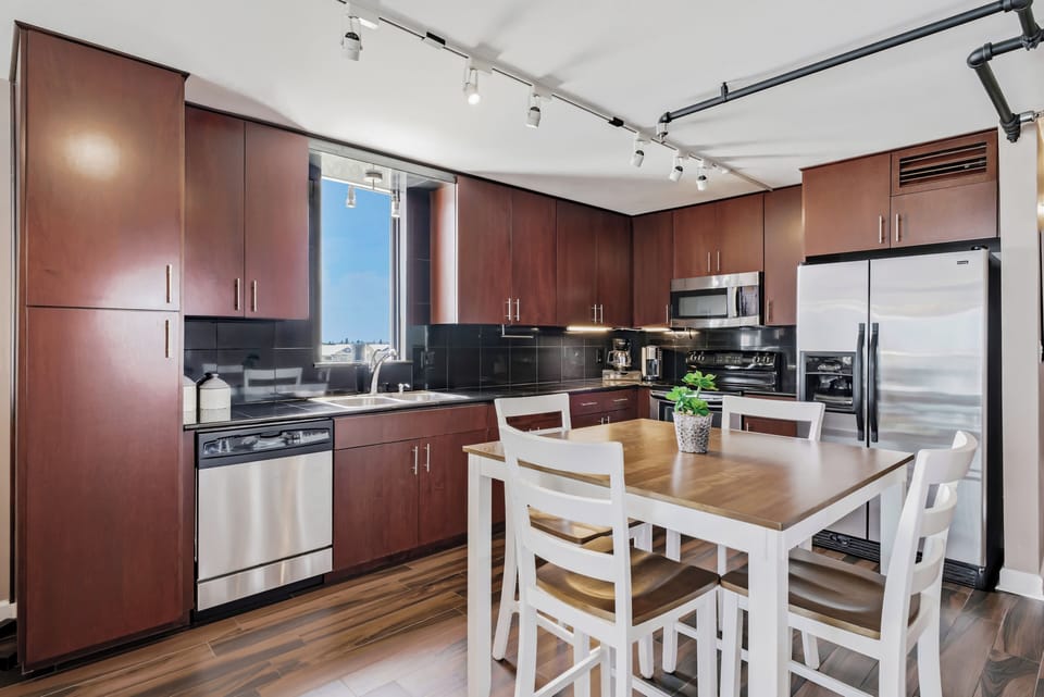 Cook your favorite meals in this modern kitchen, featuring sleek cabinetry, stainless steel appliances, and a cozy dining table perfect for your morning coffee or shared dinners.