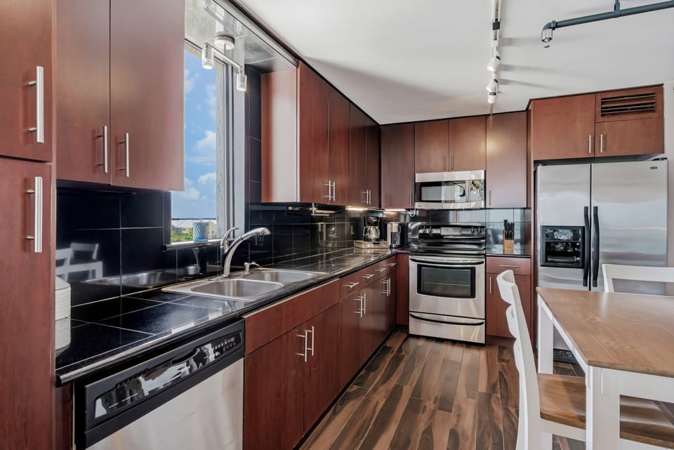 Your fully-equipped kitchen features sleek stainless appliances, rich wood cabinetry, and glossy black countertops—perfect for preparing meals during your stay.