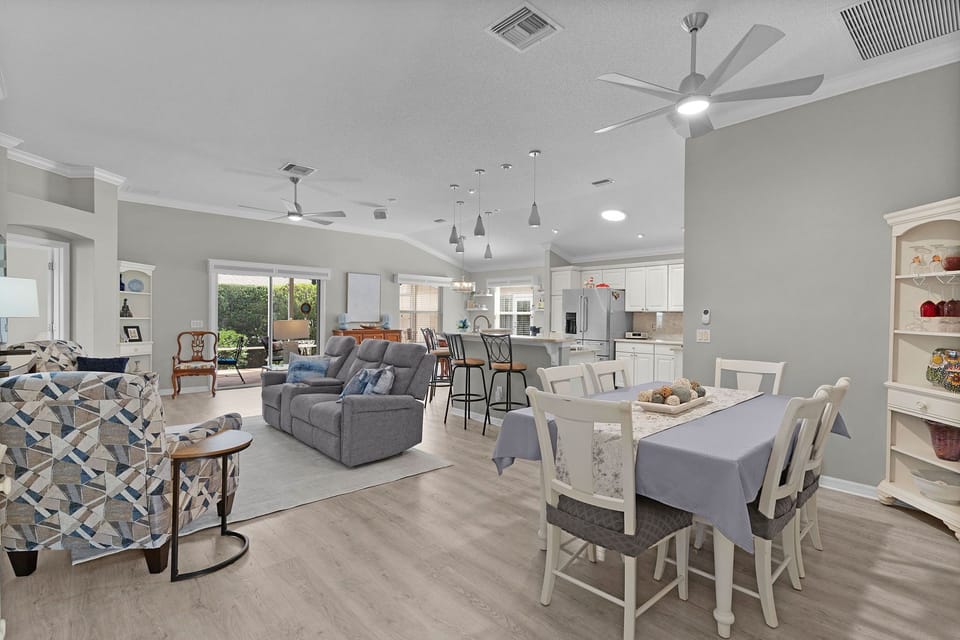 Gather around the spacious open-plan living and dining area, where high ceilings, soft neutral tones, and modern furnishings create a welcoming space for your group to relax together.