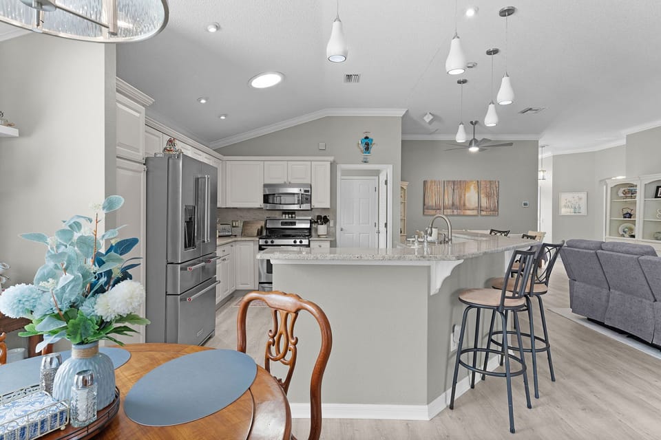 Open-concept kitchen and living space with modern stainless steel appliances, elegant pendant lighting, and a spacious island perfect for breakfasts and gatherings.