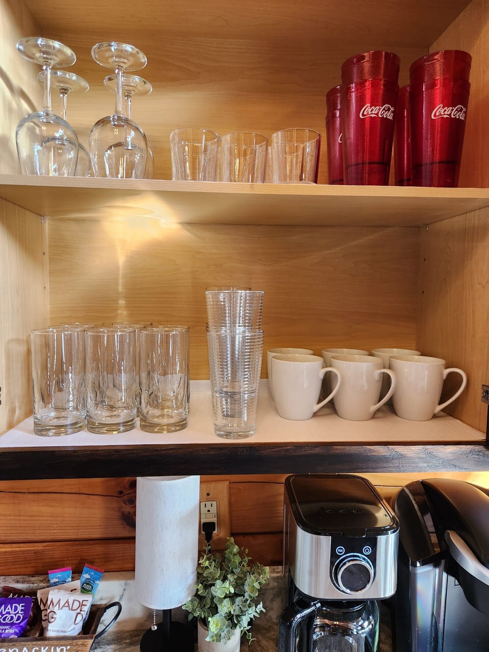 Well-stocked coffee bar with mugs, glassware, and drink essentials