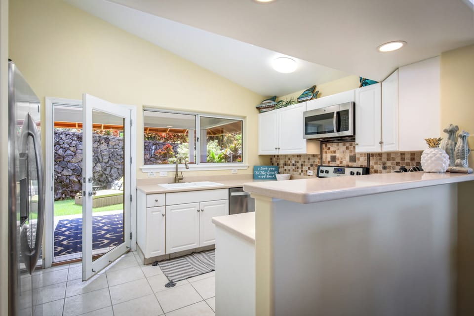 Your bright, fully-equipped kitchen awaits with modern appliances, ample counter space, and charming mosaic backsplash, opening to a peaceful backyard retreat.