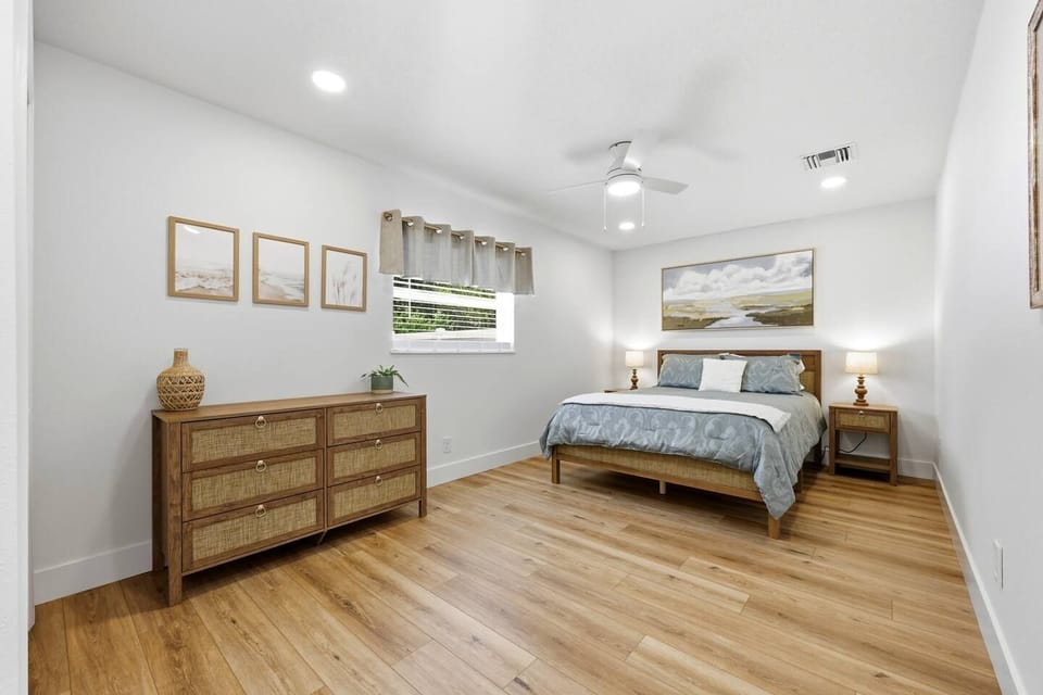 Quiet suite queen bedroom with warm wood floors and clothing storage.