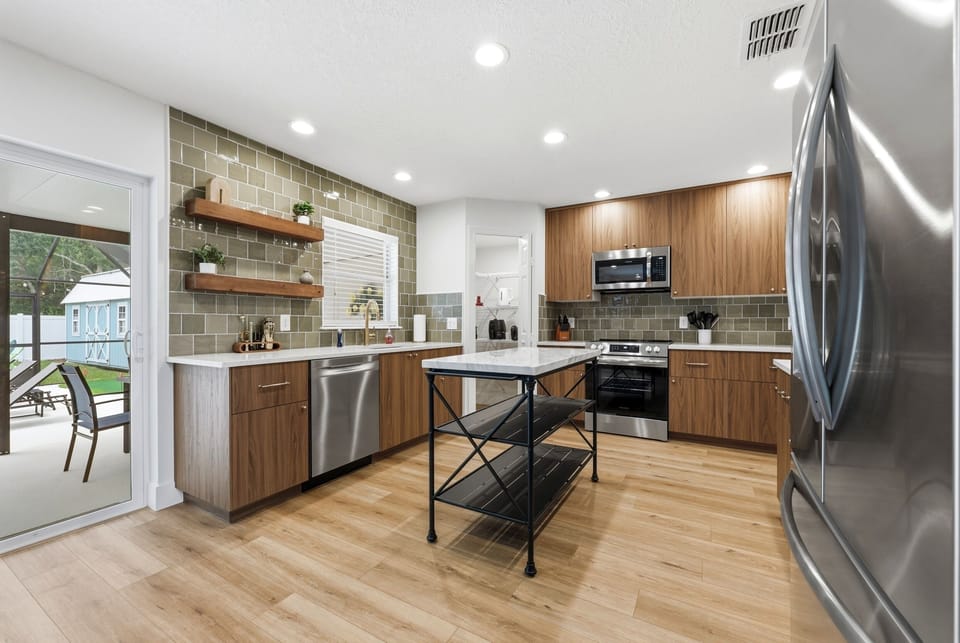 Main kitchen with island, sink, range, and patio door.