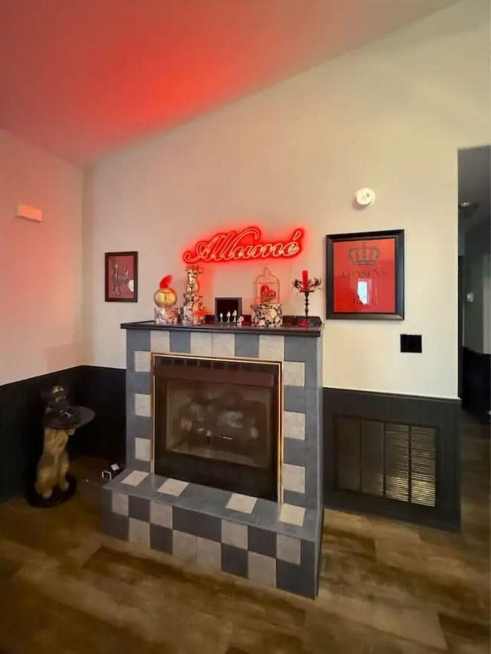 Tiled fireplace with black and gray squares topped by decorative vases and a red neon "Allume" sign.