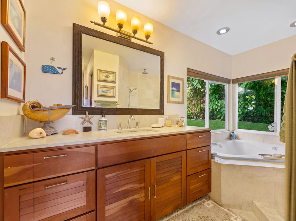 Bathroom featuring a rich wood vanity and a corner soaking tub by large windows.
