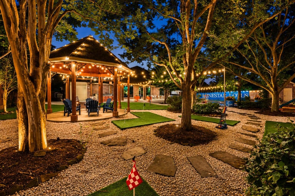 Charming lit gazebo, putting green, and resort-style courtyard at dusk