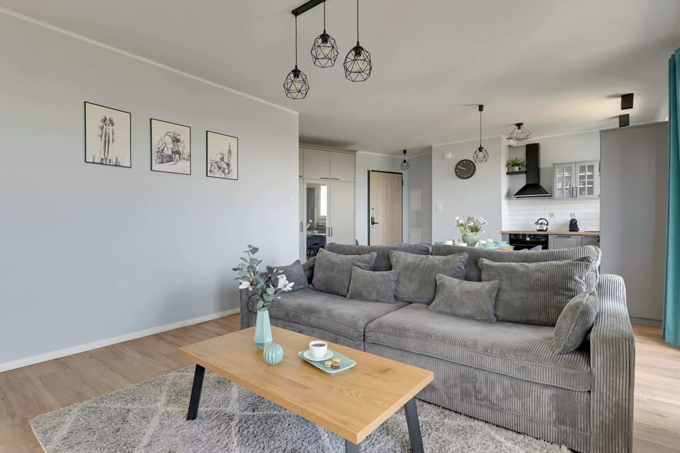 Sercem apartamentu jest jasny salon połączony z aneksem kuchennym i częścią jadalnianą. W salonie znajduje się duża, wygodna sofa, stolik kawowy oraz telewizor, dzięki czemu przestrzeń świetnie sprawdzi się do wspólnego odpoczynku.