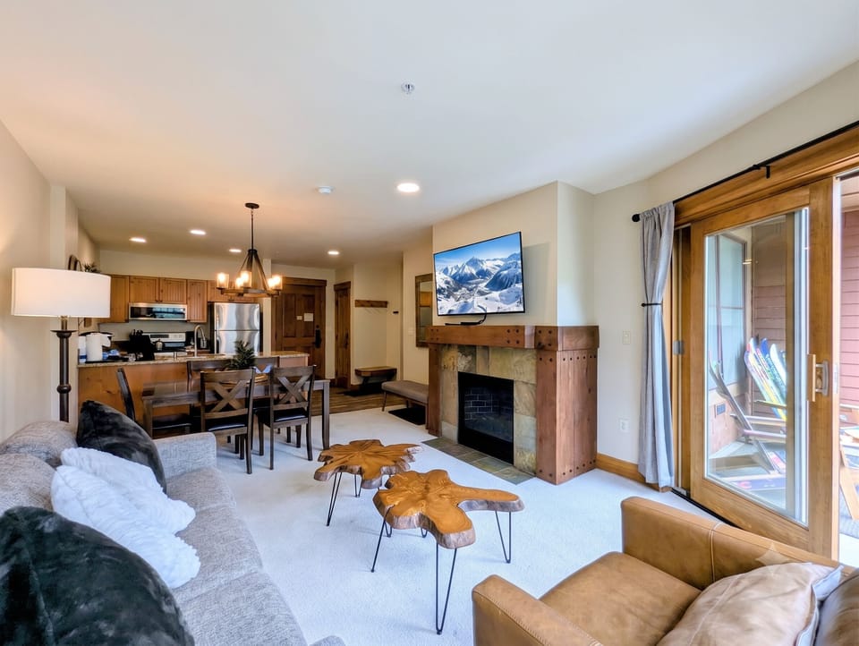 Cozy up in this inviting open-plan living space where warm wood tones and soft textures create a welcoming mountain retreat. Gather around the fireplace, dine together, and step out to your private balcony for fresh alpine air.
