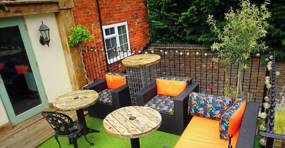 Shared upper terrace with rattan seating and festoon lights, perfect for evening drinks.