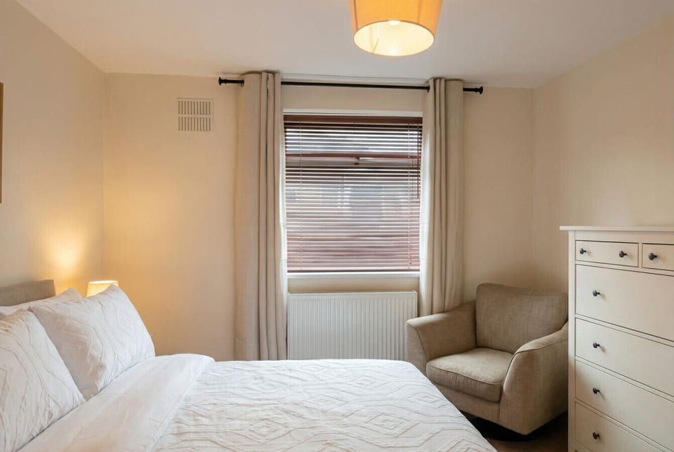 Warm bedroom corner with a cosy armchair and ample drawer storage for longer stays.