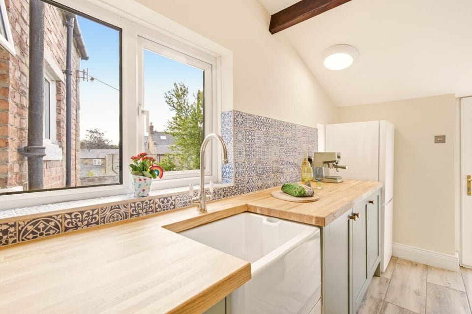 Butler sink beneath the window with patterned tiled splashback.
