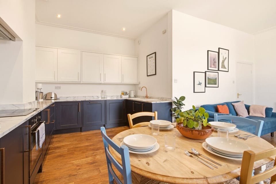 Open-plan kitchen, dining and living space with bay window outlook.