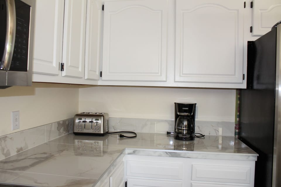 Bright kitchen with marble-look counters, coffee maker, and modern appliances