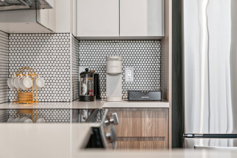 Modern kitchen coffee bar with Keurig, mugs, and sleek finishes