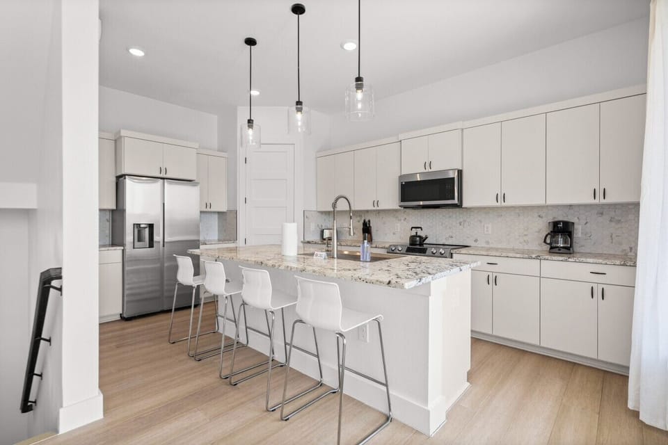 Cook and connect in the open kitchen with barstool seating for four under warm pendant lighting.